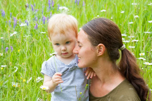 Mother and little daughter gather wild flowers