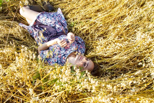 女の子は熟した耳の間の野原に横たわっている — ストック写真
