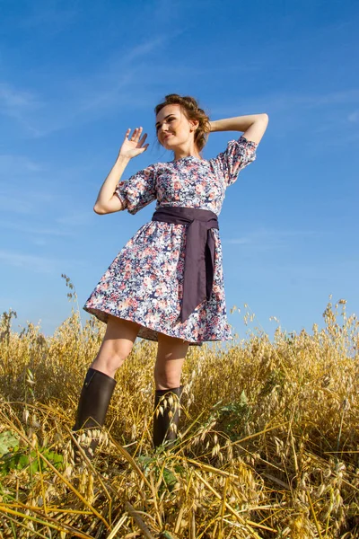 Mısır olgun kulakları arasında tarlada duran lastik çizmeli köylü kadın