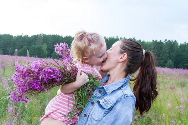Happy mom and daughter in the field among wildflowers