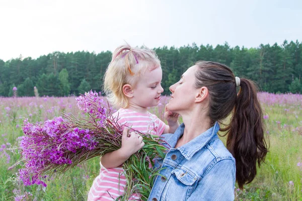 Happy mom and daughter in the field among wildflowers