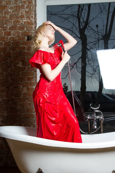 young girl in a red dress washes under the shower