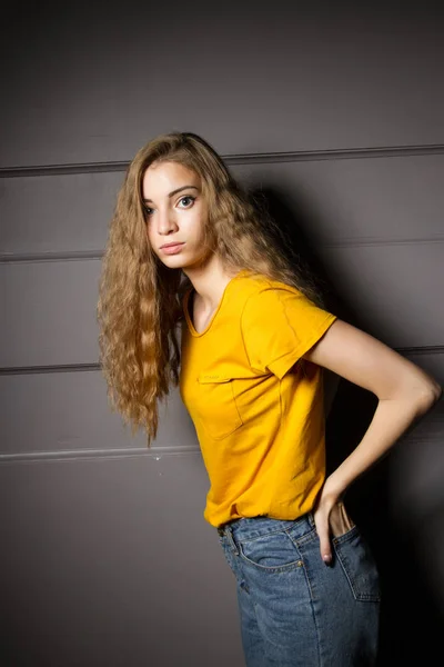 노란색 티셔츠와 청바지를 소녀가 어두운 방에서 — 스톡 사진
