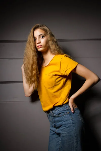 Chica Una Camiseta Amarilla Pantalones Vaqueros Levanta Contra Una Pared — Foto de Stock