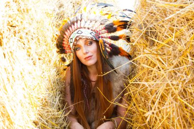Bir saman yığını tarafından Hint savaşçısı gibi giyinmiş kızıl saçlı kız