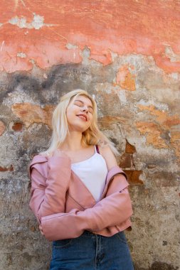 pembe bir ceket güzel sarışın serpme sıva ile harap bir duvar tarafından duruyor