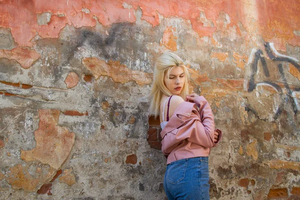 Belle Blonde Dans Une Veste Rose Tient Près Mur Délabré Images De Stock Libres De Droits