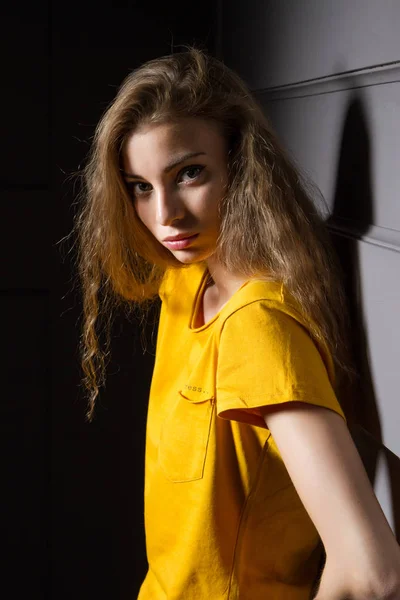 Young Girl Bright Yellow Shirt Stands Dark Room Wall — Stock Photo, Image