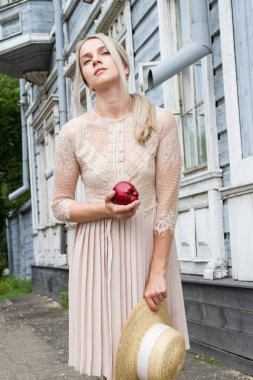 Hasır şapkalı güzel genç sarışın elinde kırmızı bir elma tutar