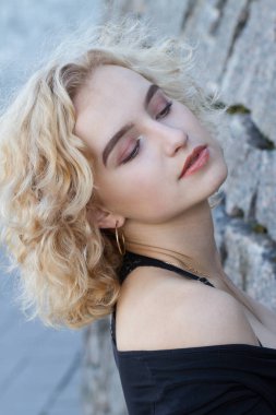 Arkaplanda parlak makyajlı genç bir sarışının portresi.