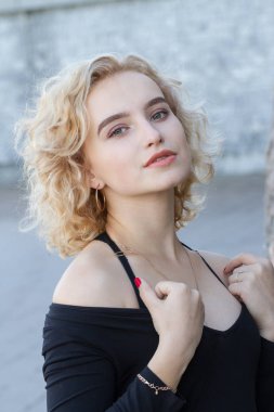 Arkaplanda parlak makyajlı genç bir sarışının portresi.