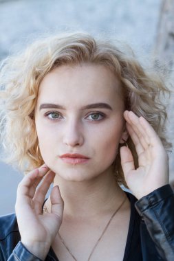 Arkaplanda parlak makyajlı genç bir sarışının portresi.