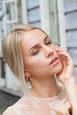 Parlak makyajlı güzel bir genç kız eski bir ahşap binanın arkasında poz veriyor.