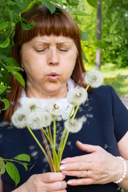 Elinde bir buket karahindiba olan yaşlı bir kadın.