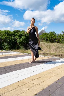 Açık yaz çocuk parkında poz veren uzun siyah elbiseli bir kız.