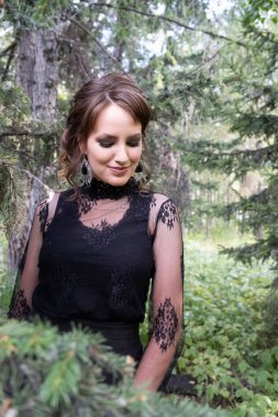 Kozalaklı ormanın arka planında parlak makyajlı güzel bir genç kızın portresi. Gün ışığı