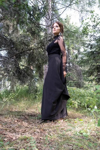夏の森を背景に長い黒いドレスを着た若い女の子 — ストック写真