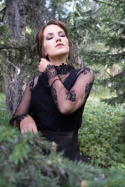 Dziewczyna Jasnym Makijażem Czarnej Sukience Tle Drzew Iglastych — Zdjęcie stockowe
