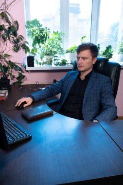 Genç adam ofiste masada oturuyor.