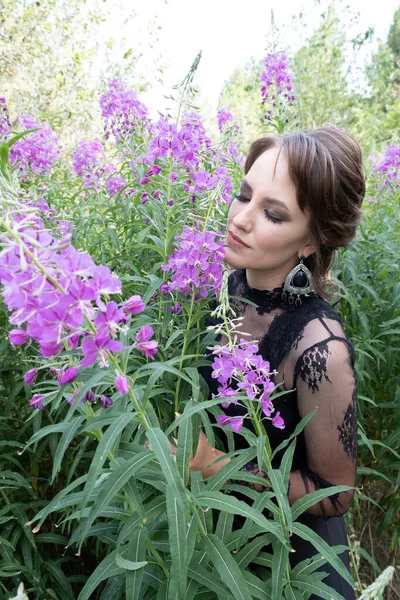 明るいメイクの女の子 野の花の間で黒いドレスで — ストック写真