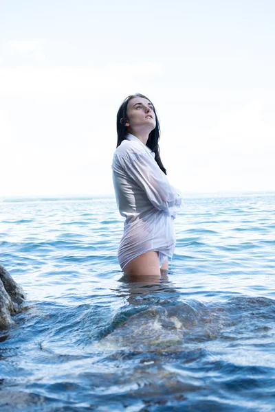 若いです女の子でぬれた白いシャツは水の中に立っている — ストック写真