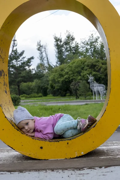 Маленька Дівчинка Лежить Всередині Металевого Овалу Фоні Парку — стокове фото