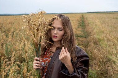 Deri ceketli, bir buket yulaf kulaklı kız.