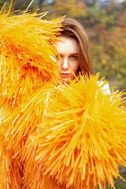 Kızıl saçlı genç kız bir sonbahar manzarasının arka planında poz veriyor.