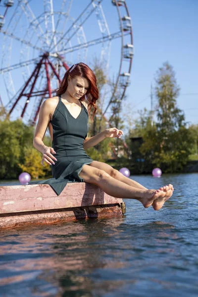 Girl splashing feet in water sitting on the pier