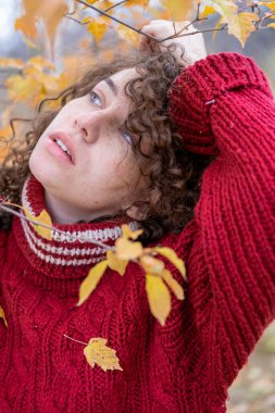 Sonbahar parkında kalın kazaklı bir kız.