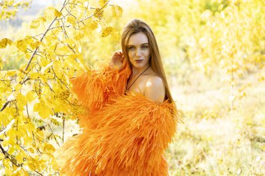 Sonbahar ormanında gece makyajlı ve parlak elbiseli bir kız.