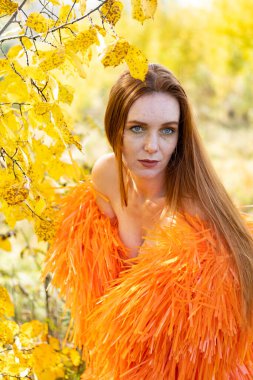 Sonbahar ormanında gece makyajlı ve parlak elbiseli bir kız.