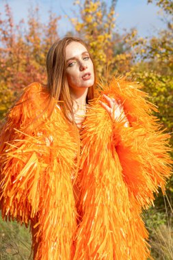 Sonbahar ormanında gece makyajlı ve parlak elbiseli bir kız.