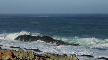Manzaralı deniz manzarası, dalgalar yükseldiğinde kayaların üzerinde dalgalanır.