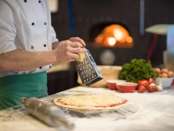 Şef Mutfak Masasında Taze Pizza Hamurunun Üzerine Peynir Serpiyor — Stok fotoğraf