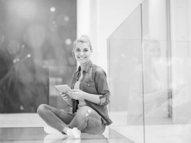 Güzel genç bir kadın evde tablet bilgisayar kullanıyor.