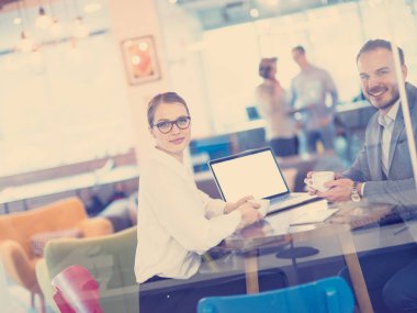 Bir sonraki toplantı için dizüstü bilgisayar kullanan girişimciler kahve içerken ve yaratıcı ofiste fikirleri tartışırken...