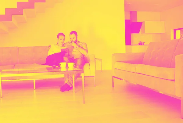 ロマンチックなカップルはソファソファのリビングルームで読書タブレットコンピュータで豪華な家でリラックス — ストック写真