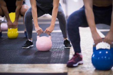 Çapraz fitness stüdyosunda kettlebell egzersizleri yapan bir grup sağlıklı genç sporcu.