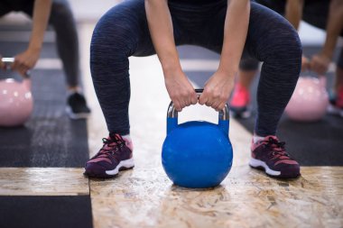 Çapraz fitness stüdyosunda kettlebell egzersizleri yapan bir grup sağlıklı genç sporcu.