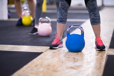 Çapraz fitness stüdyosunda kettlebell egzersizleri yapan bir grup sağlıklı genç sporcu.