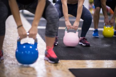 Çapraz fitness stüdyosunda kettlebell egzersizleri yapan bir grup sağlıklı genç sporcu.