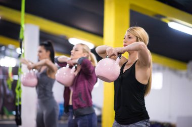 Çapraz fitness stüdyosunda kettlebell egzersizleri yapan bir grup sağlıklı genç sporcu.