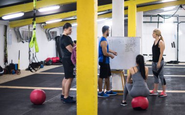 Antrenman kursu. Spor salonunda egzersiz yapmadan önce bir grup genç sporcu antrenörden talimat alıyor.