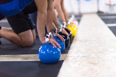 Bir grup sağlıklı genç sporcu spor salonunda kettlebell ile şınav çekiyorlar.