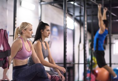 Bir grup genç kaslı sporcu, Cross fitness eğitiminin bir parçası olarak barfiks çekiyorlar.