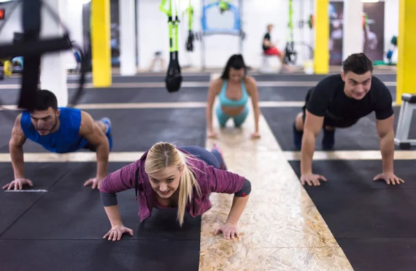 在跨健身健身房做俯卧撑的年轻健康人小组 — 图库照片