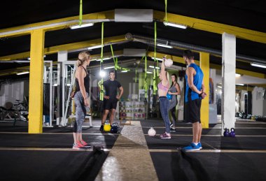 Çapraz fitness stüdyosunda kettlebell egzersizleri yapan bir grup sağlıklı genç sporcu.