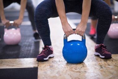 Çapraz fitness stüdyosunda kettlebell egzersizleri yapan bir grup sağlıklı genç sporcu.