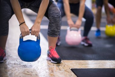 Çapraz fitness stüdyosunda kettlebell egzersizleri yapan bir grup sağlıklı genç sporcu.